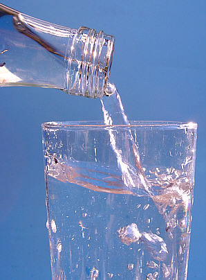 A bottle pouring still mineral water into a glass